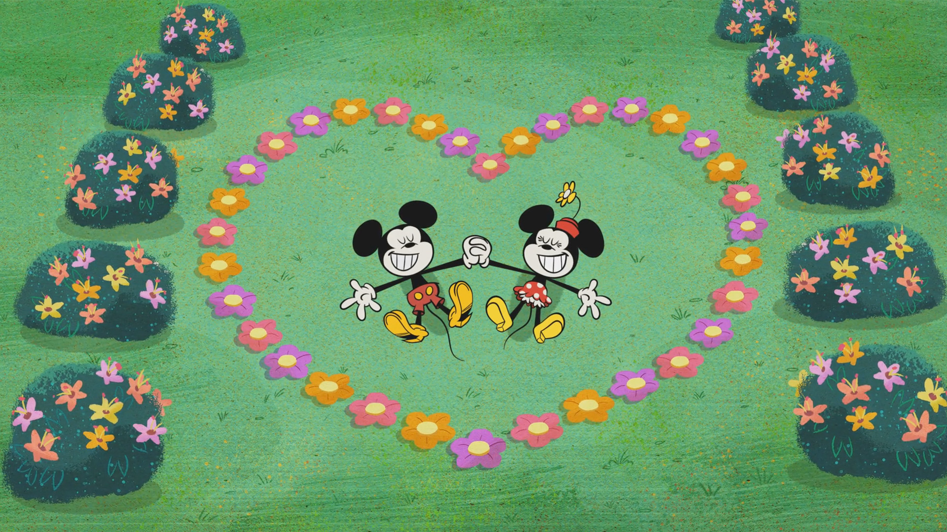 Mickey and Minnie from the Wonderful World of Mickey Mouse lay on the grass hand in hand smiling with a heart made of flowers around them.