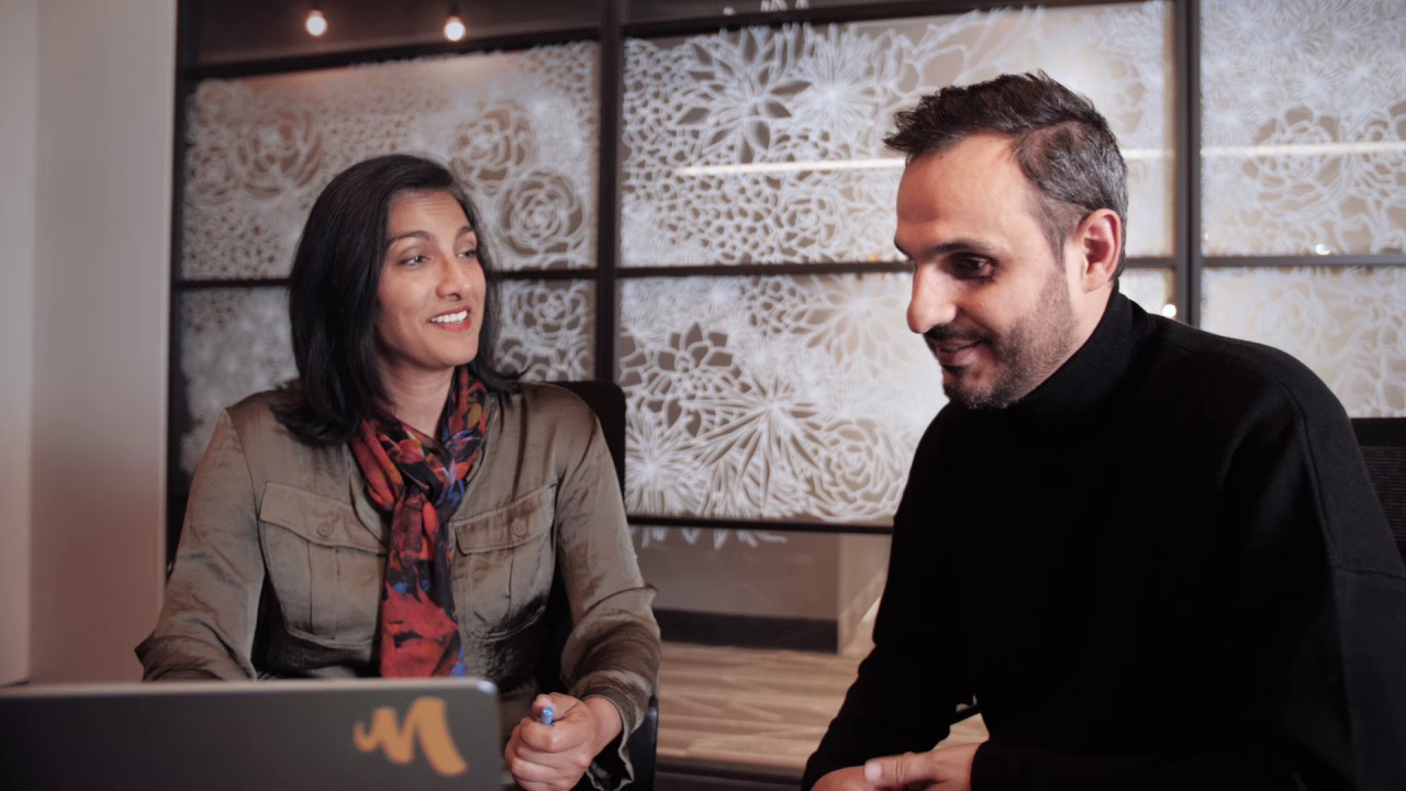 Executives from Mercury Filmworks talk to each other as they look over a laptop.