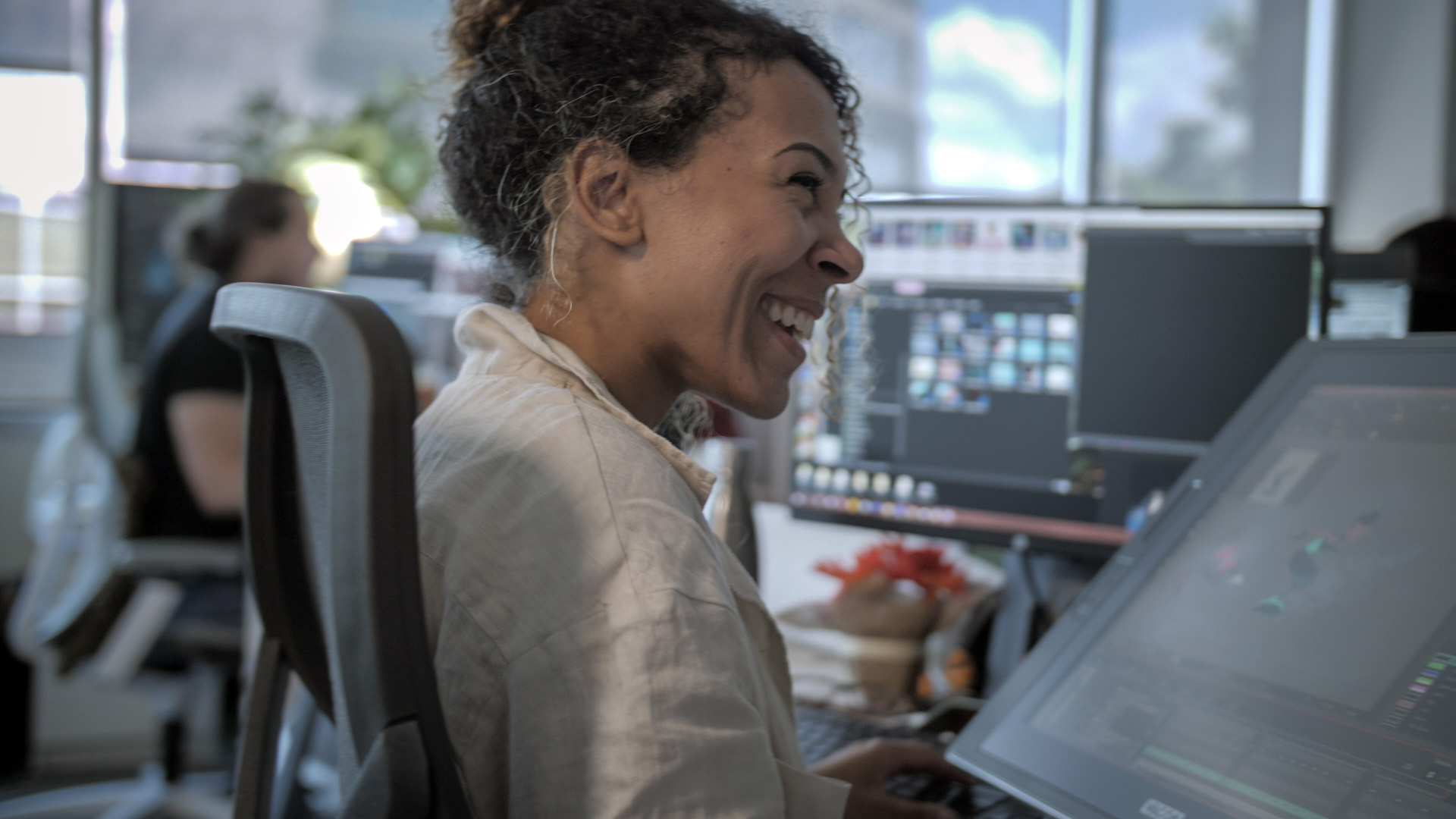 An animator from Mercury Filmworks laughes as she draws on her cintiq in studio.